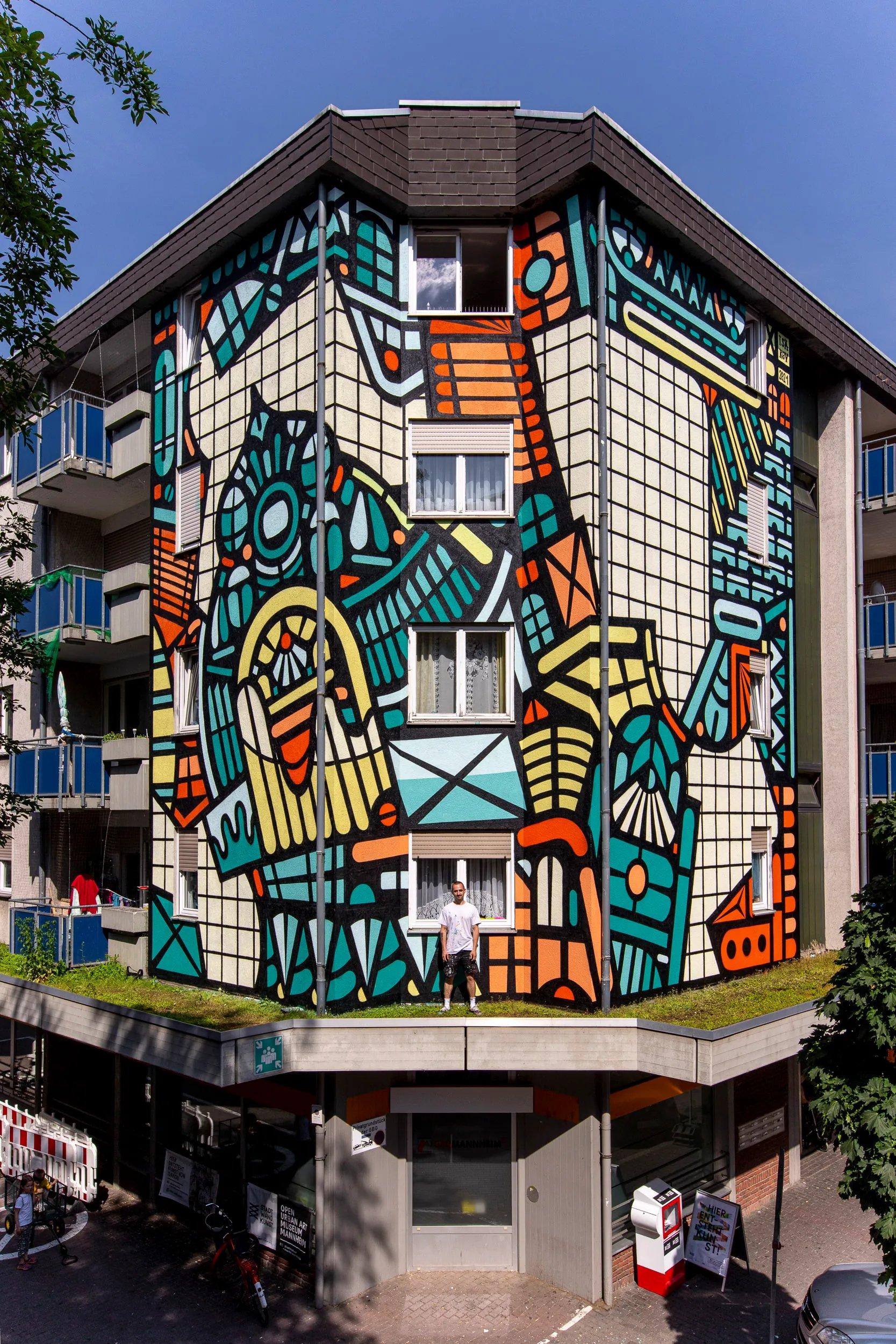 아티스트가 크레인을 타고 대형 벽화를 그리고 있는 모습