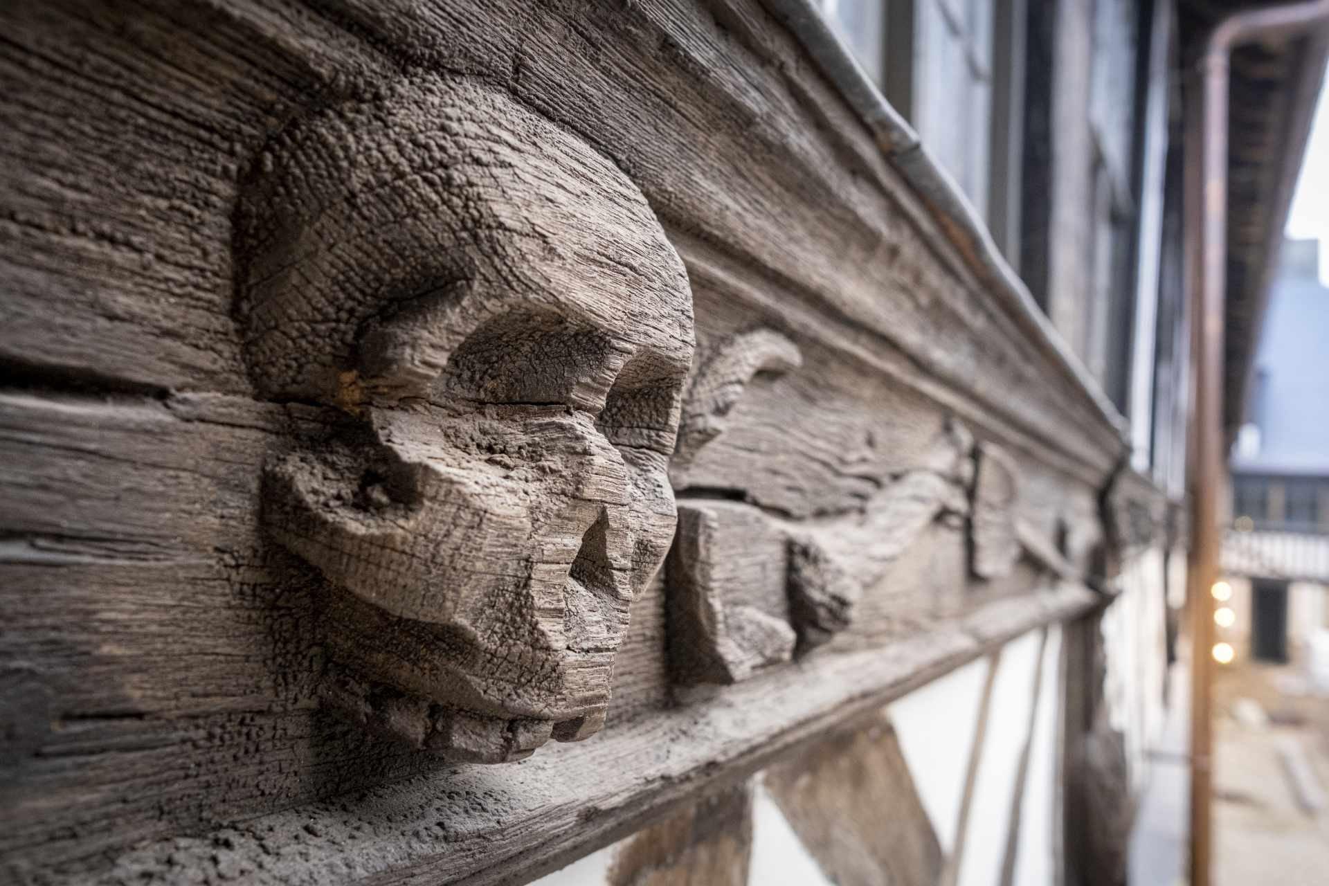 마카브르 조각이 새겨진 목조 기둥 앞